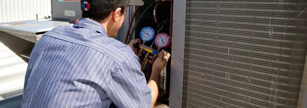 HVAC technician servicing a condenser unit in Fayetteville
