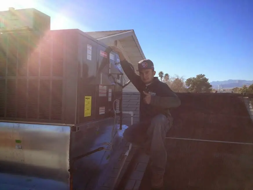 HVAC technician performing AC Tune-Up on a rooftop unit in Fayetteville